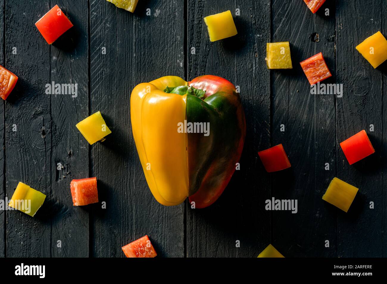 Red And Yellow Peppers Sliced on Black Wooden Surface Stock Photo