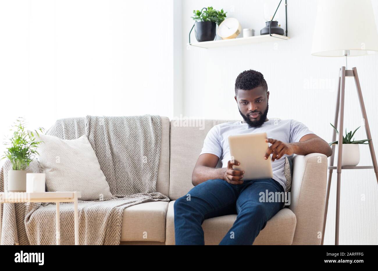 Young african man browsing on digital tablet at home Stock Photo