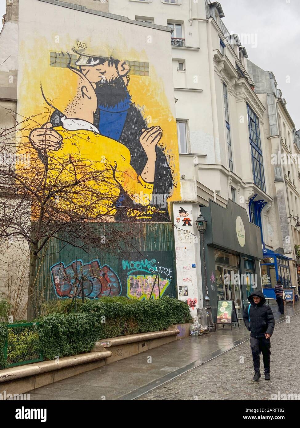 STREET ART :TINTIN AND HADDOCK CAPTAIN KISSING EACH OTHER ON A PARIS WALL Stock Photo