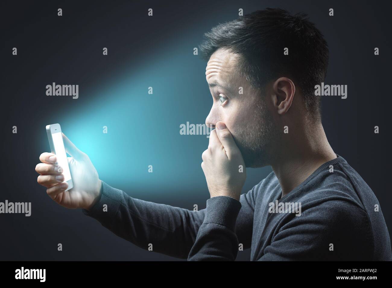 Appalled man looking at his glowing smartphone screen Stock Photo