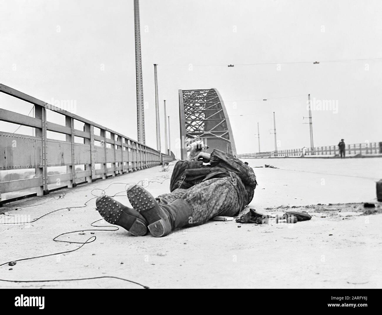 Operation Market Garden, Arnhem, the Netherlands, 1944: The bridge at Nijmegen after it had been captured by the 82nd (US) Airborne Division. A dead German SS lies where he fell during the attack. Note the heavy boots and the full camouflage outfit. In the right background, a lone GI patrols Stock Photo