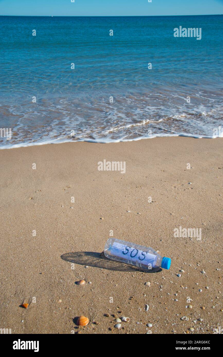 Sea plastic contamination. SOS message in a plastic bottle on the sea shore. Stock Photo