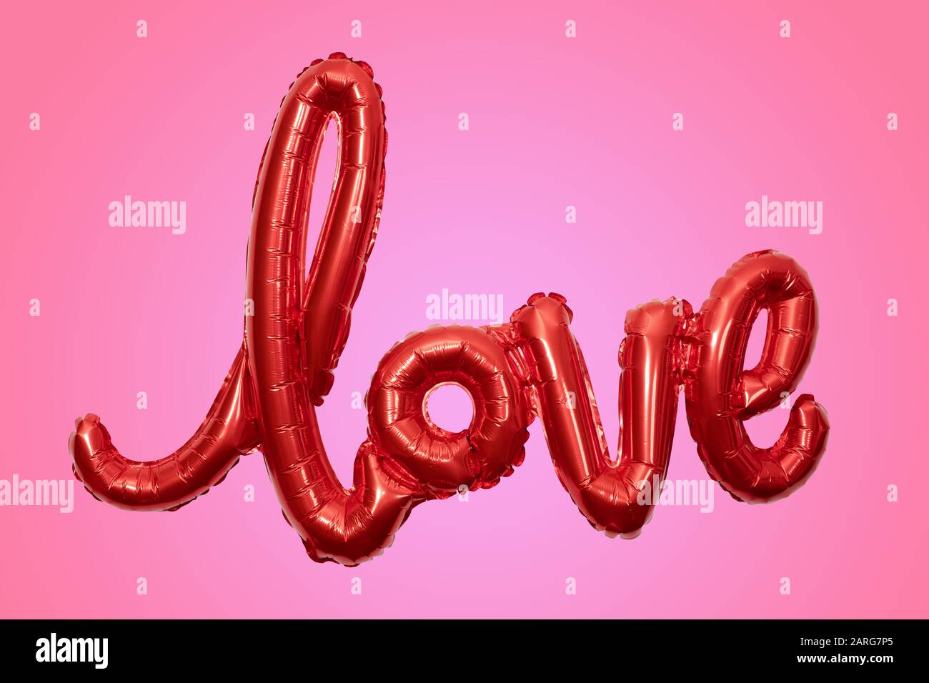 Inflated party balloon forming the word love on pink background Stock Photo