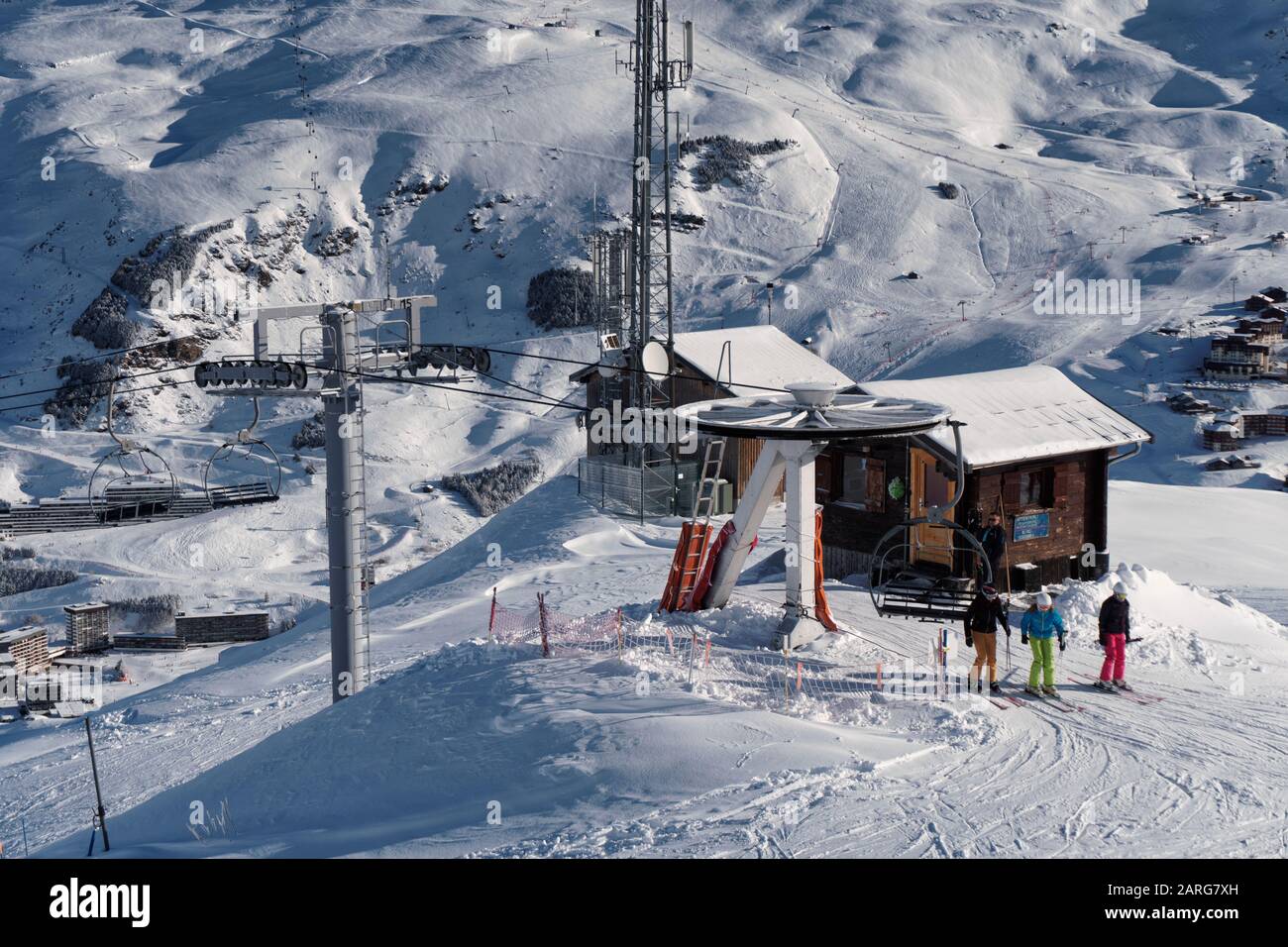 3 skiers get off the Rocher Noir chair lift on La Masse in the French ski resort of Les Menuires. Stock Photo