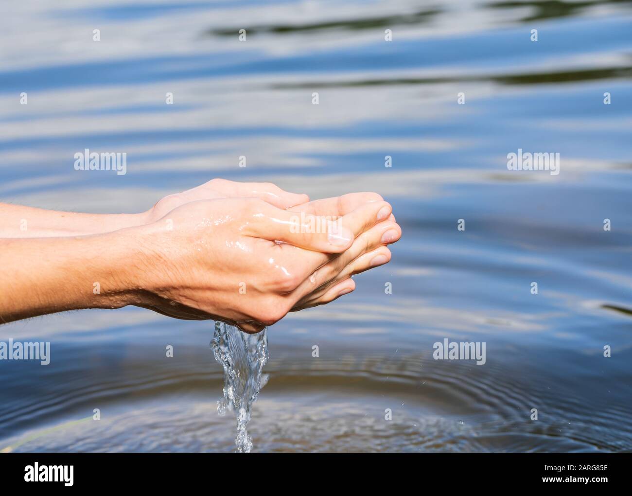 Woman taking raw unfiltered water from a natural source by cupped hands