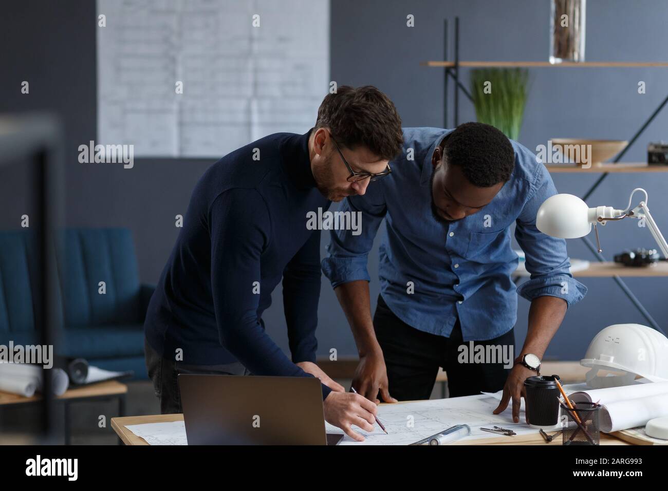 Multiracial engineer team working in office with blue prints and ...