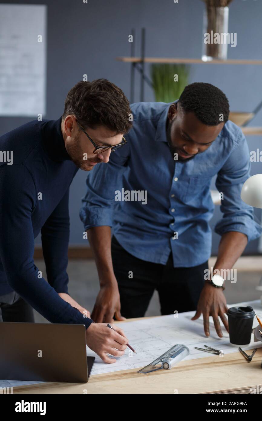 Multiracial engineer team working in office with blue prints and ...