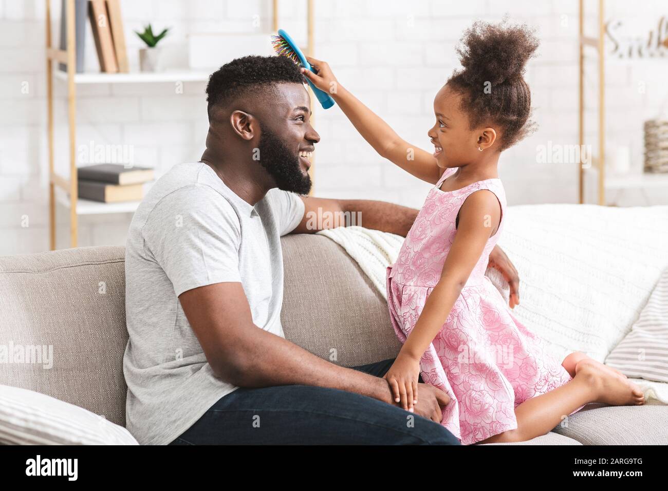 Little girl brushing her young dad's hair Stock Photo