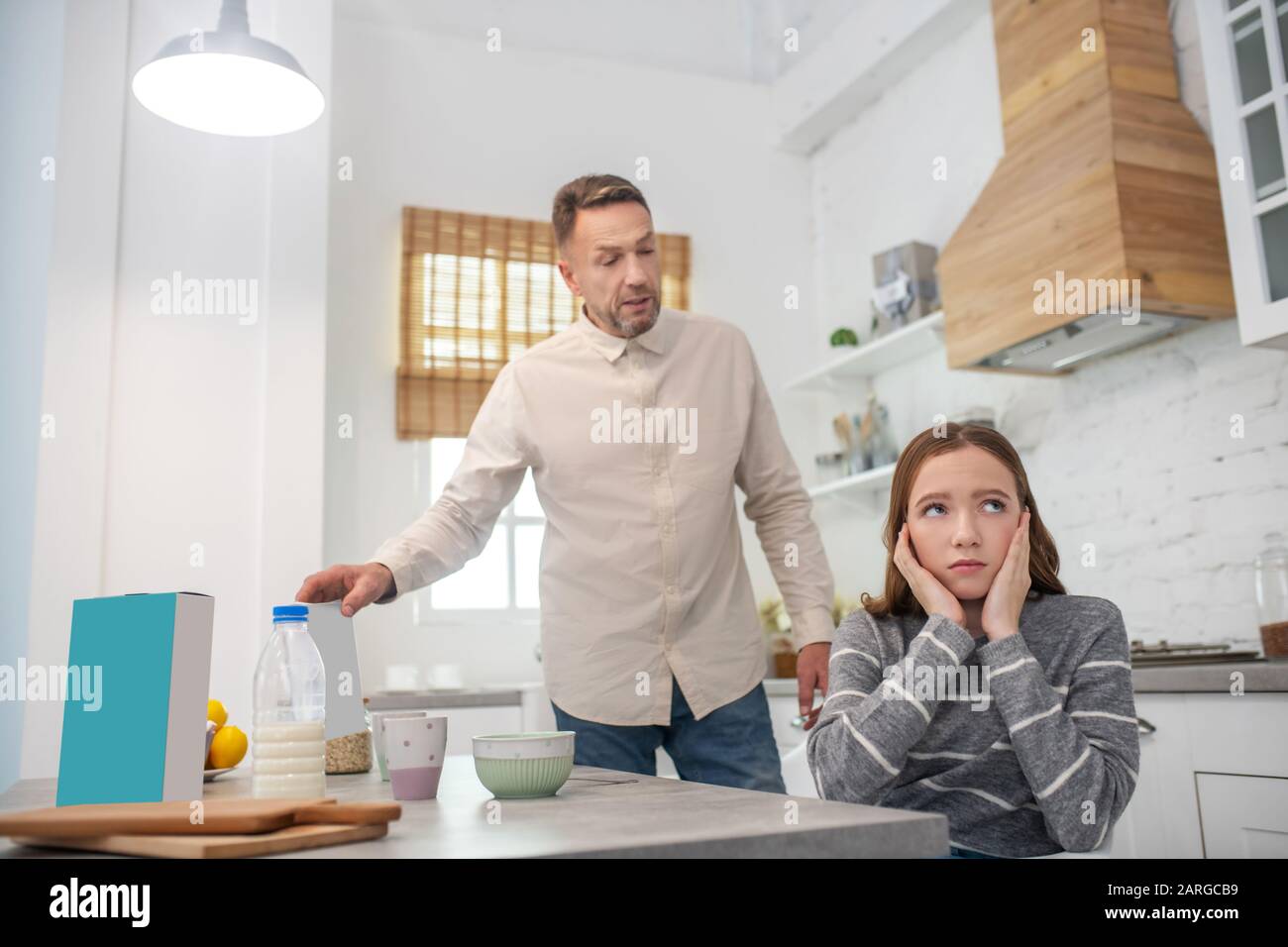 Father proving daughters the benefits of cereal with milk. Stock Photo