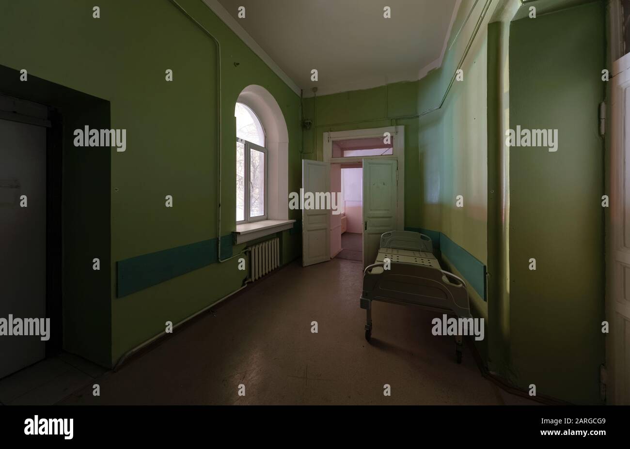 Green corridor with an empty hospital bed in an abandoned hospital Stock Photo