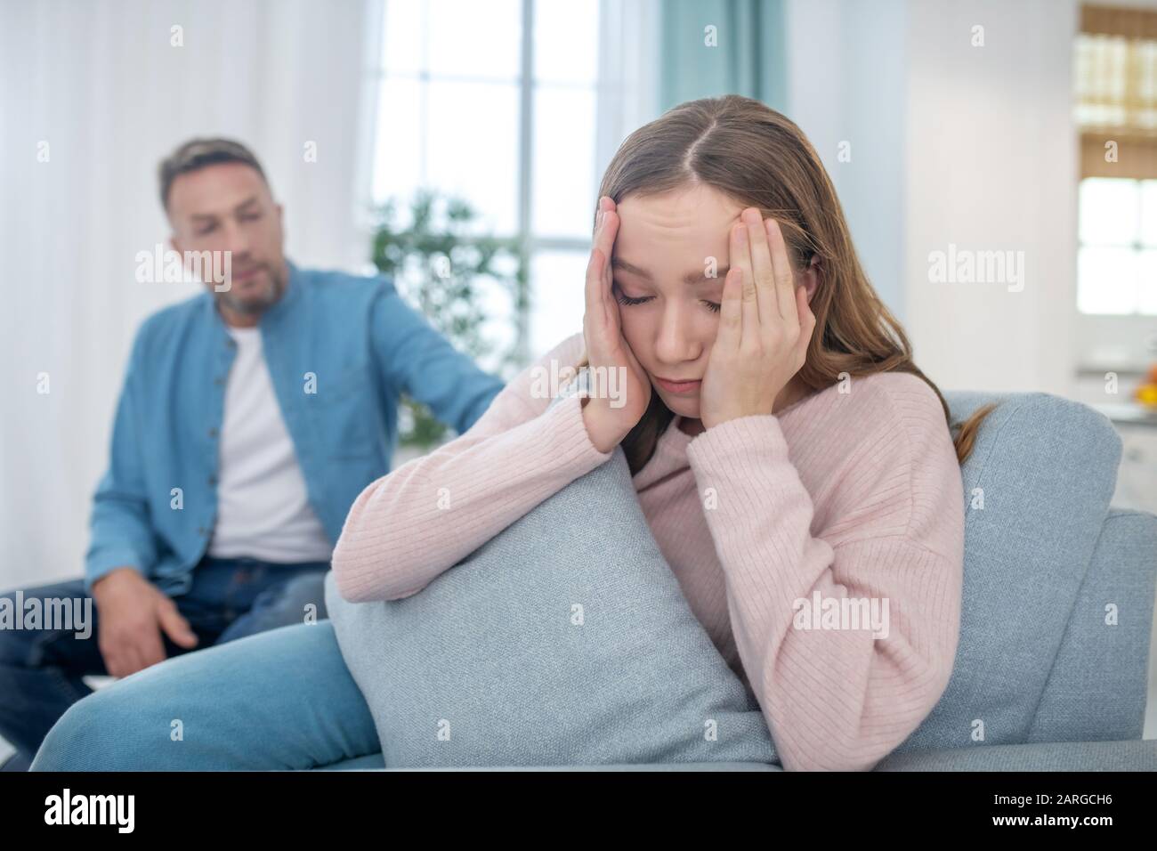 Daughter covering her face with hands, turning away from father. Stock Photo