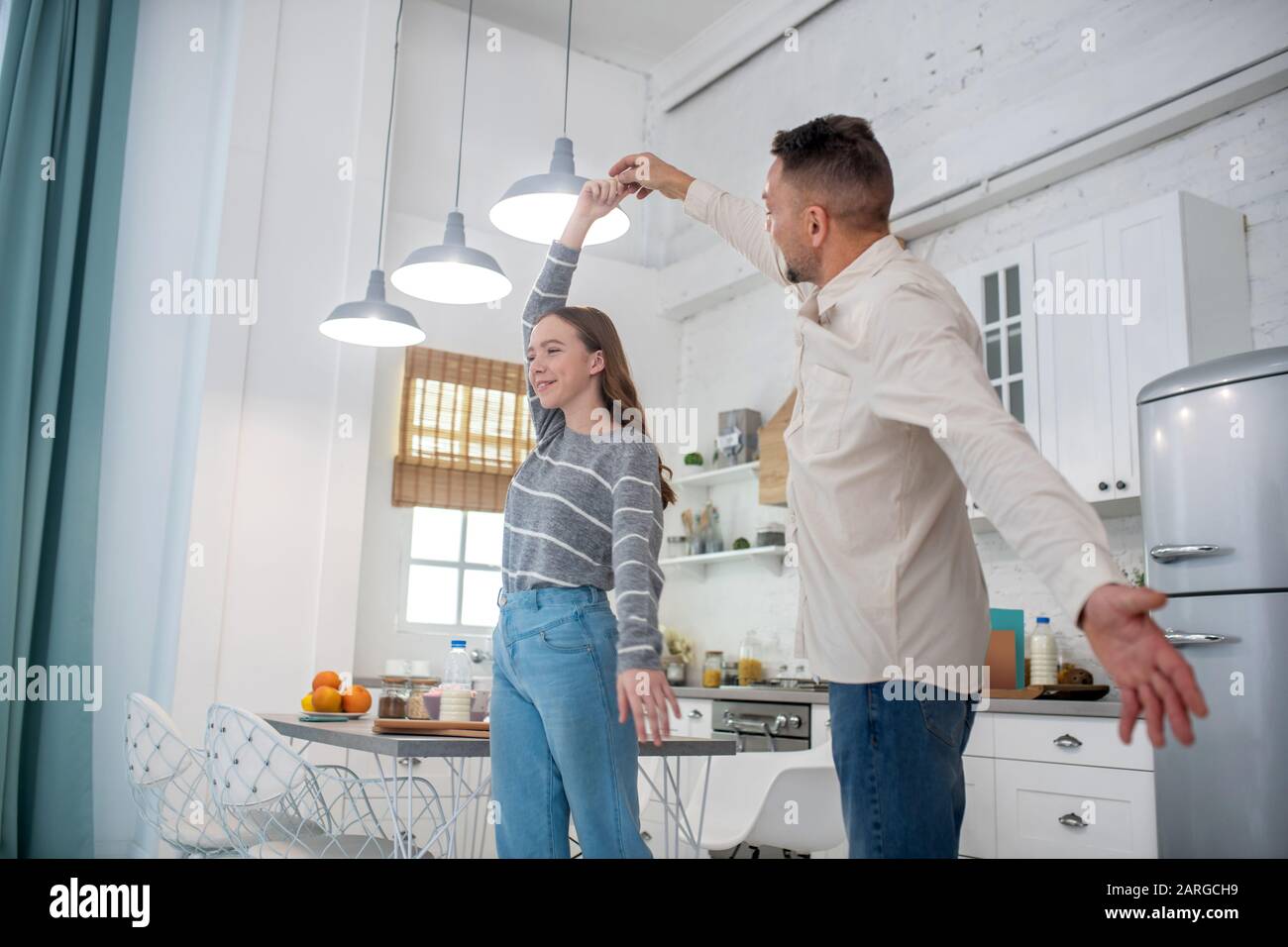 Daughter teenager dancing with dad in the kitchen. Stock Photo