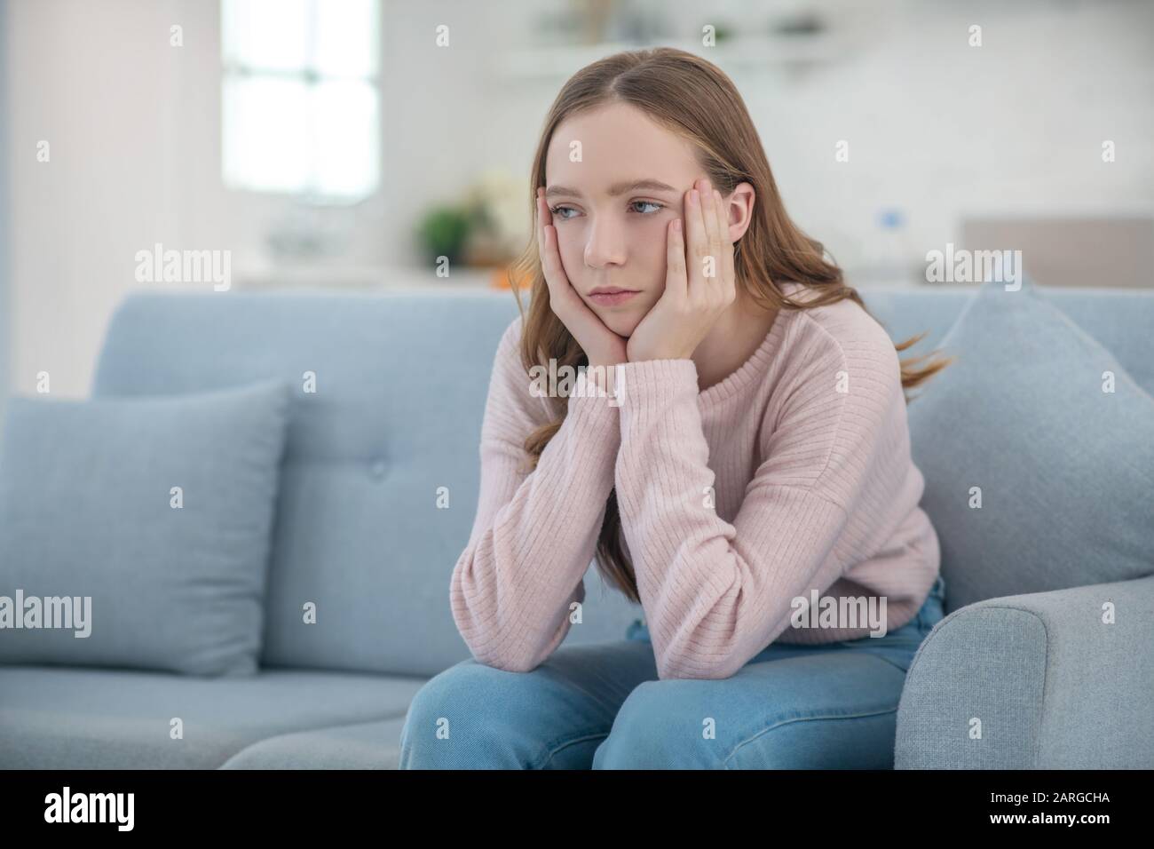 Sad teenager girl sitting at home on the couch Stock Photo - Alamy