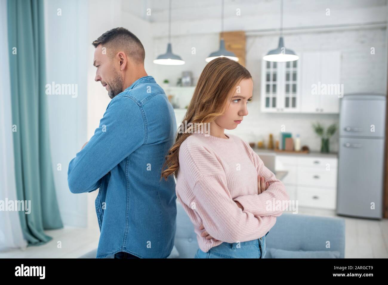 Father and daughter standing back to back, arms crossed Stock Photo Alamy