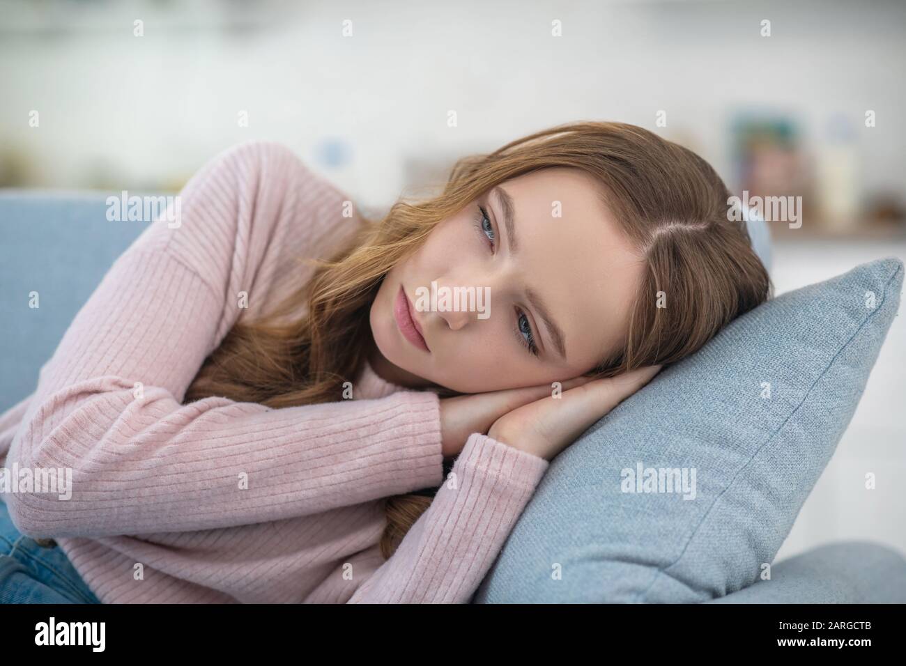 Sad girl lying on a sofa at home Stock Photo - Alamy