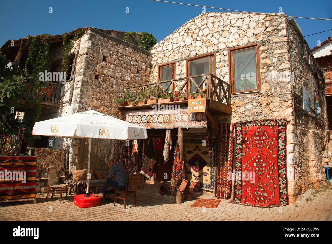 Vendor selling rugs at the town center in front of a traditional house
