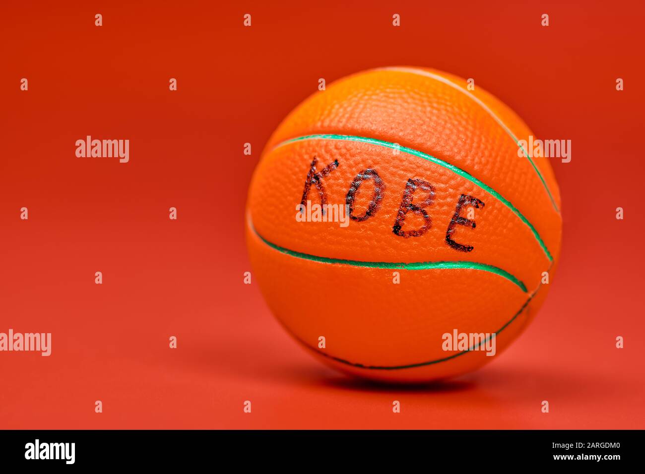 Basketball ball with KOBE text, red background, copy space. Famous basketball player concept. Stock Photo