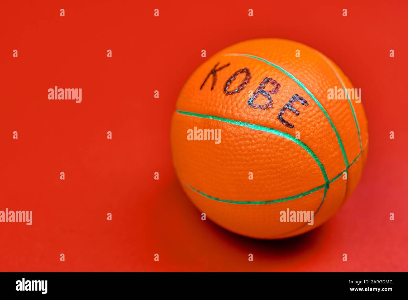 Basketball ball with KOBE text, red background, copy space. Famous basketball player concept. Stock Photo
