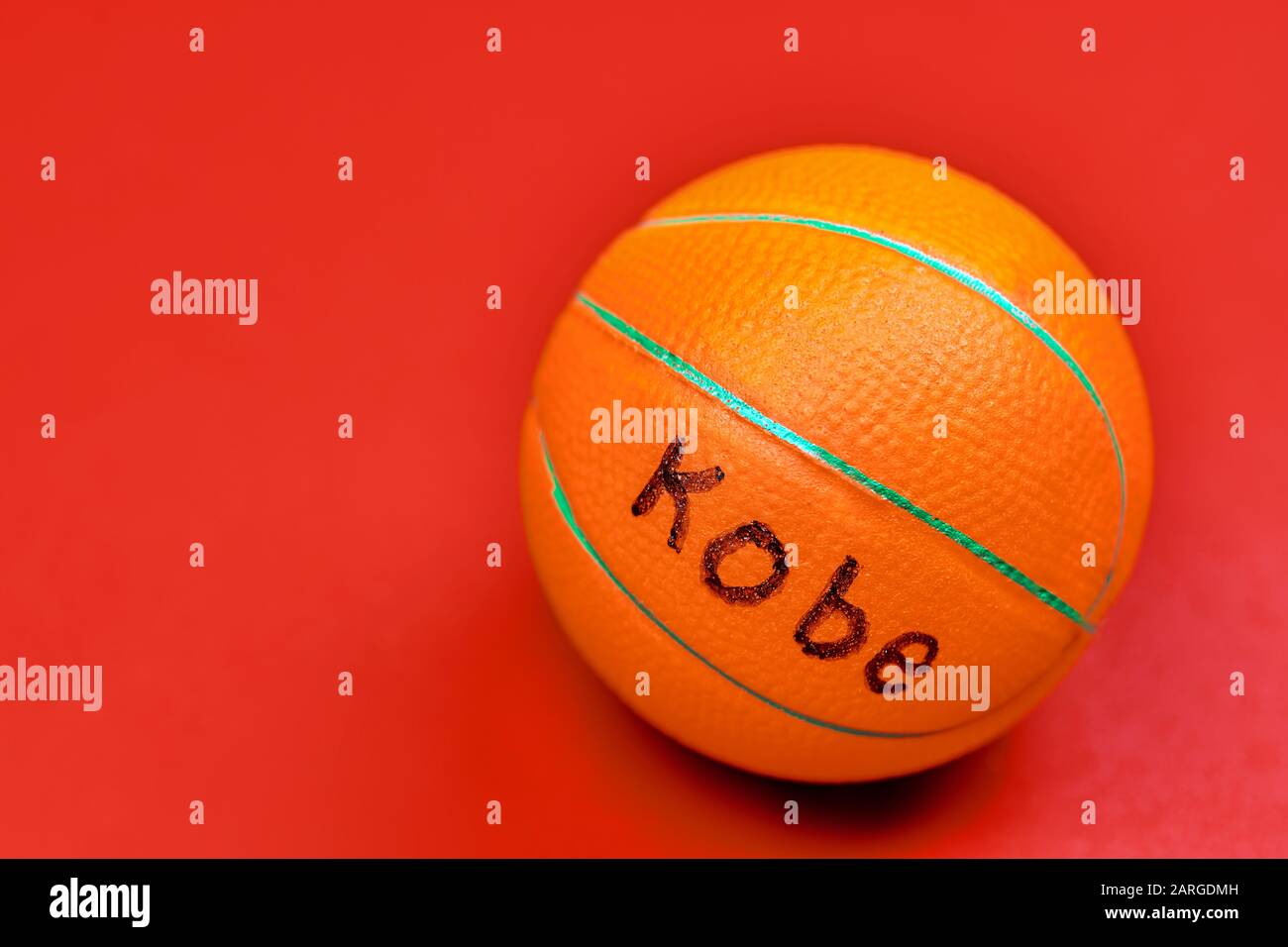 Basketball ball with KOBE text, red background, copy space. Famous basketball player concept. Stock Photo