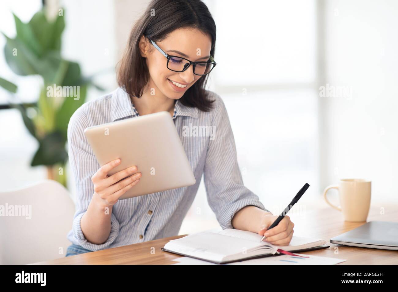Left handed Girl Holding Tablet And Writing In Notebook Stock Photo Alamy Left handed girl holding tablet and writing in notebook stock photo alamy