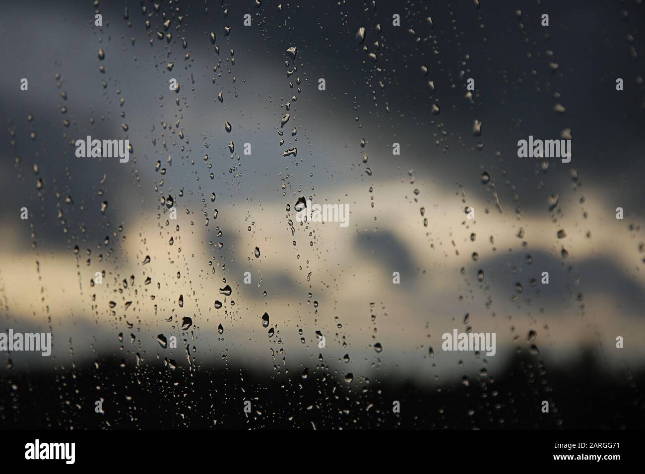 Raindrops on the window pane. Black, gray, white gradient on blurry background. Cloudy rainy weather outside the window. Cooling, raining, bad weather Stock Photo