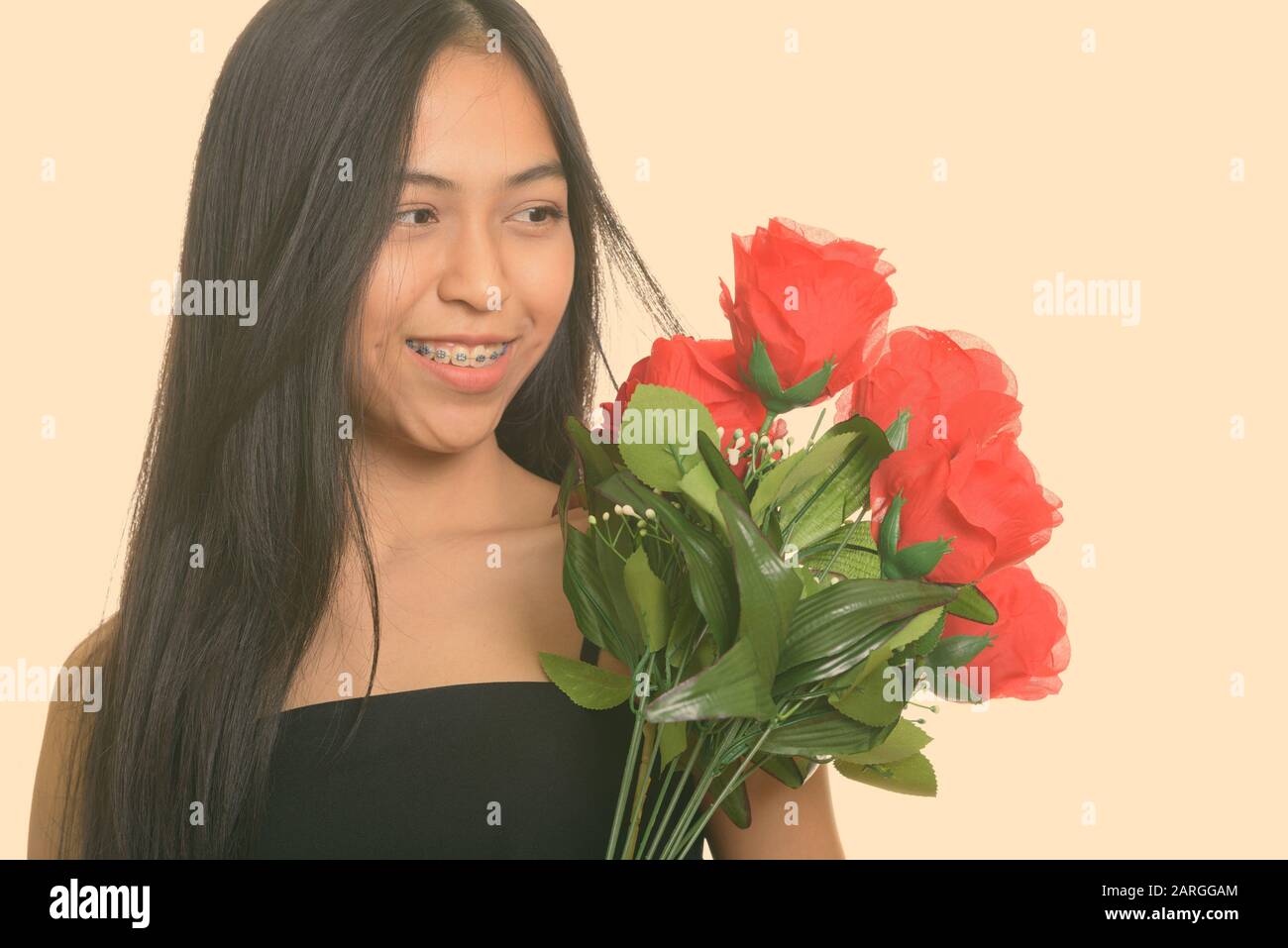 Young happy Asian teenage girl smiling while holding and looking at red ...