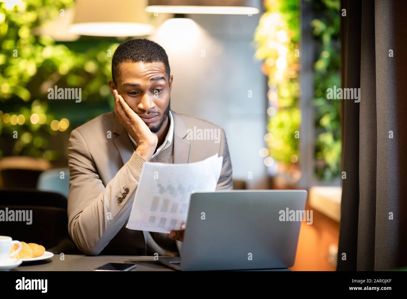 Afro businessman looking at documents with graphs Stock Photo