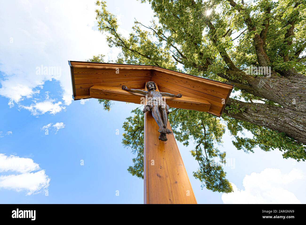 Corridor cross with Jesus in front of blue cloudz sky and branches - Calvary Stock Photo