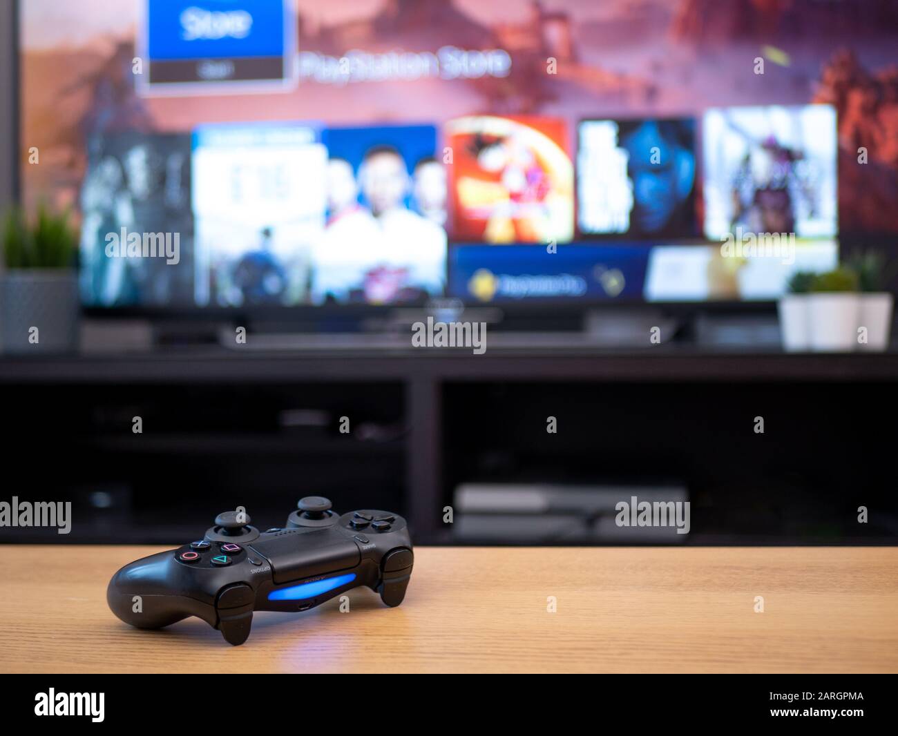 UK, Jan 2020: Sony dualshock 4 controller remote for Playstation 4 with tv screen in background Stock Photo