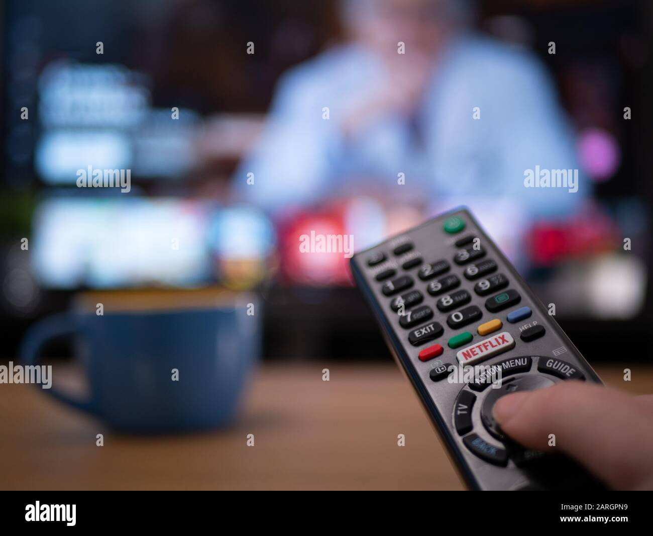 UK, Jan 2020: close up of TV remote with television behind showing Netflix menu documentary Stock Photo