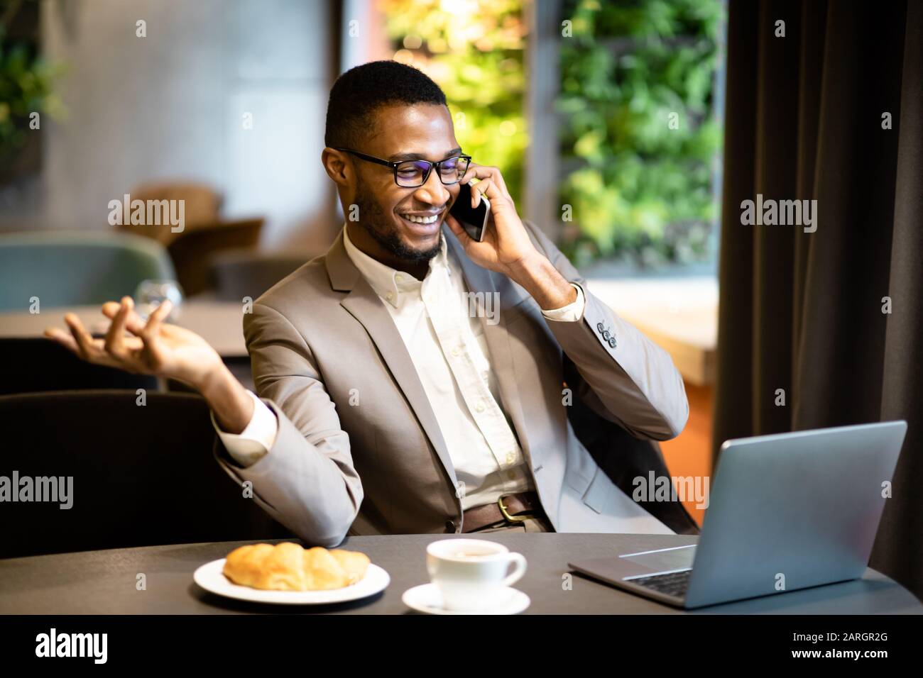 Black guy talking on phone sitting at the table Stock Photo