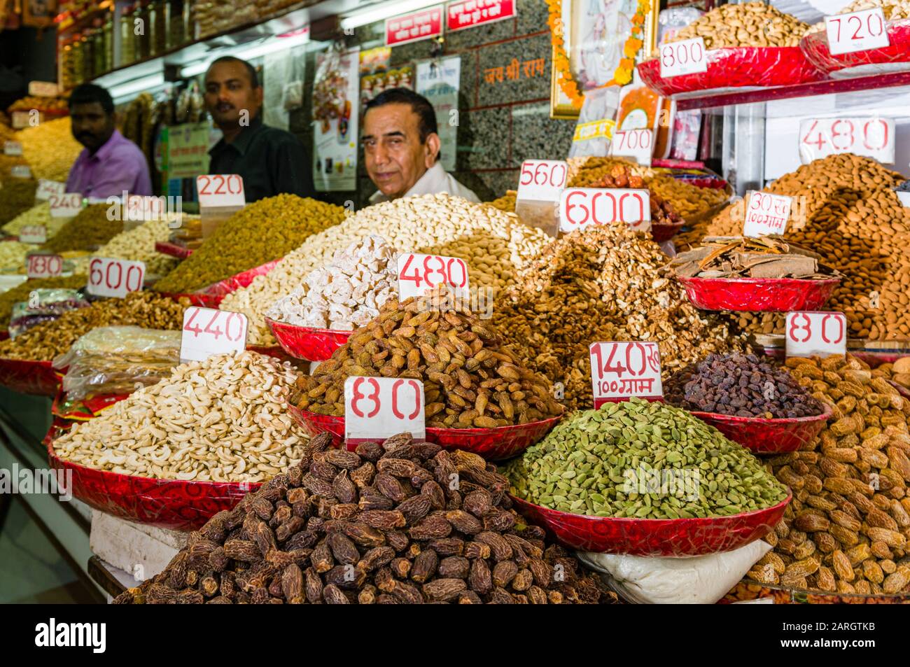 A salesman is selling nuts and many different spices in his shop in the the spice market in Old Delhi Stock Photo