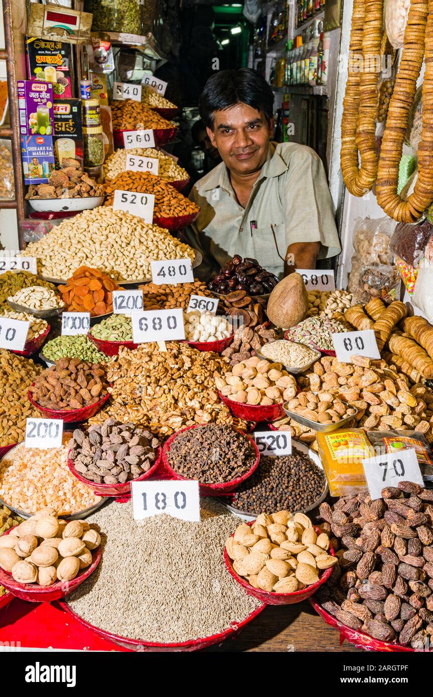 A salesman is selling nuts and many different spices in his shop in the the spice market in Old Delhi Stock Photo