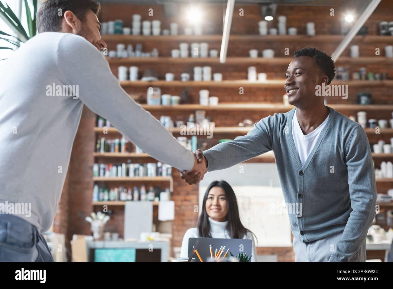 Young business partners shaking hands during group meeting Stock Photo