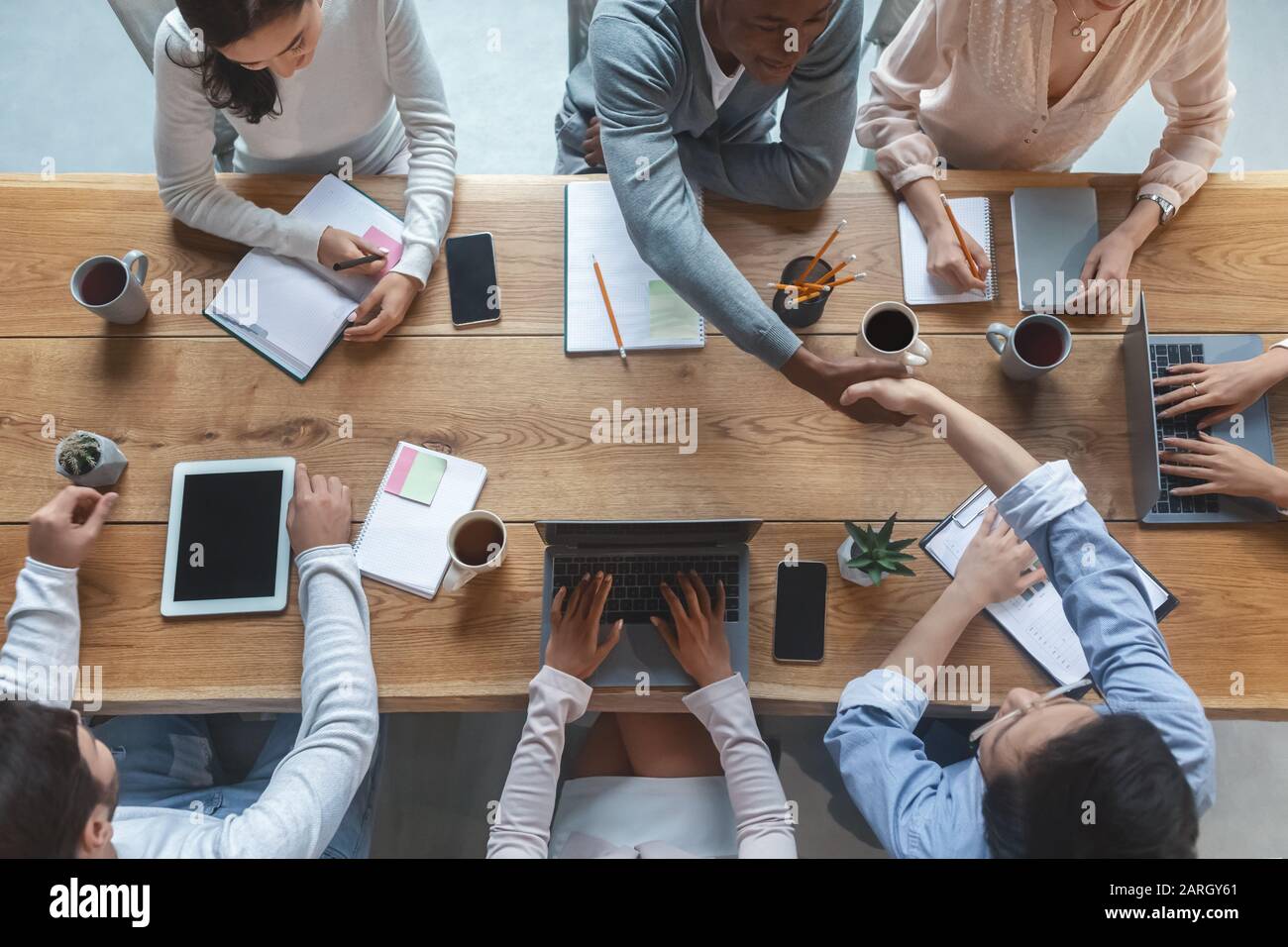 Top view of colleagues shaking hands during group business meeting Stock Photo