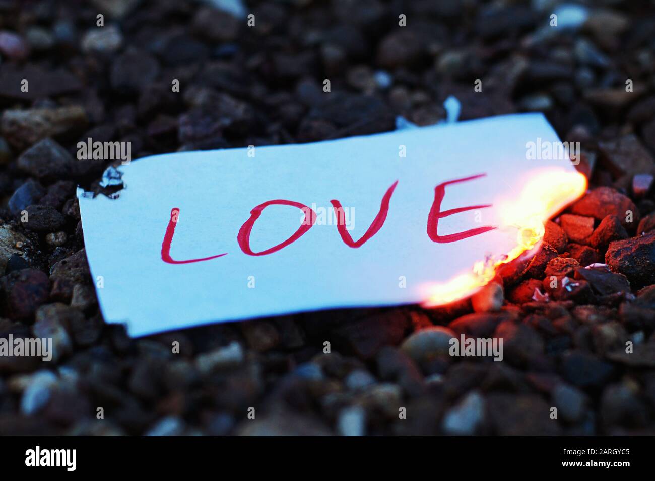 Paper note with word love burning at dusk. End of love story and breakup idea Stock Photo