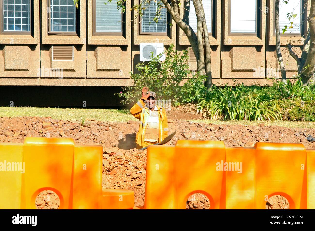 Road worker with road traffic safety barriers in front of building