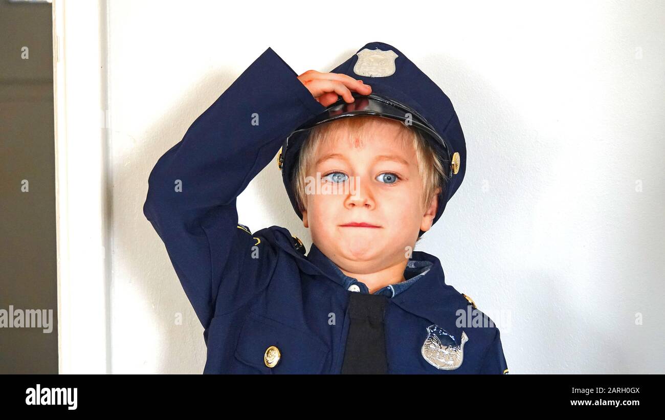 Six Year Old Boy Wearing Police Officer Fancy Dress  Outfit, Saluting Stock Photo