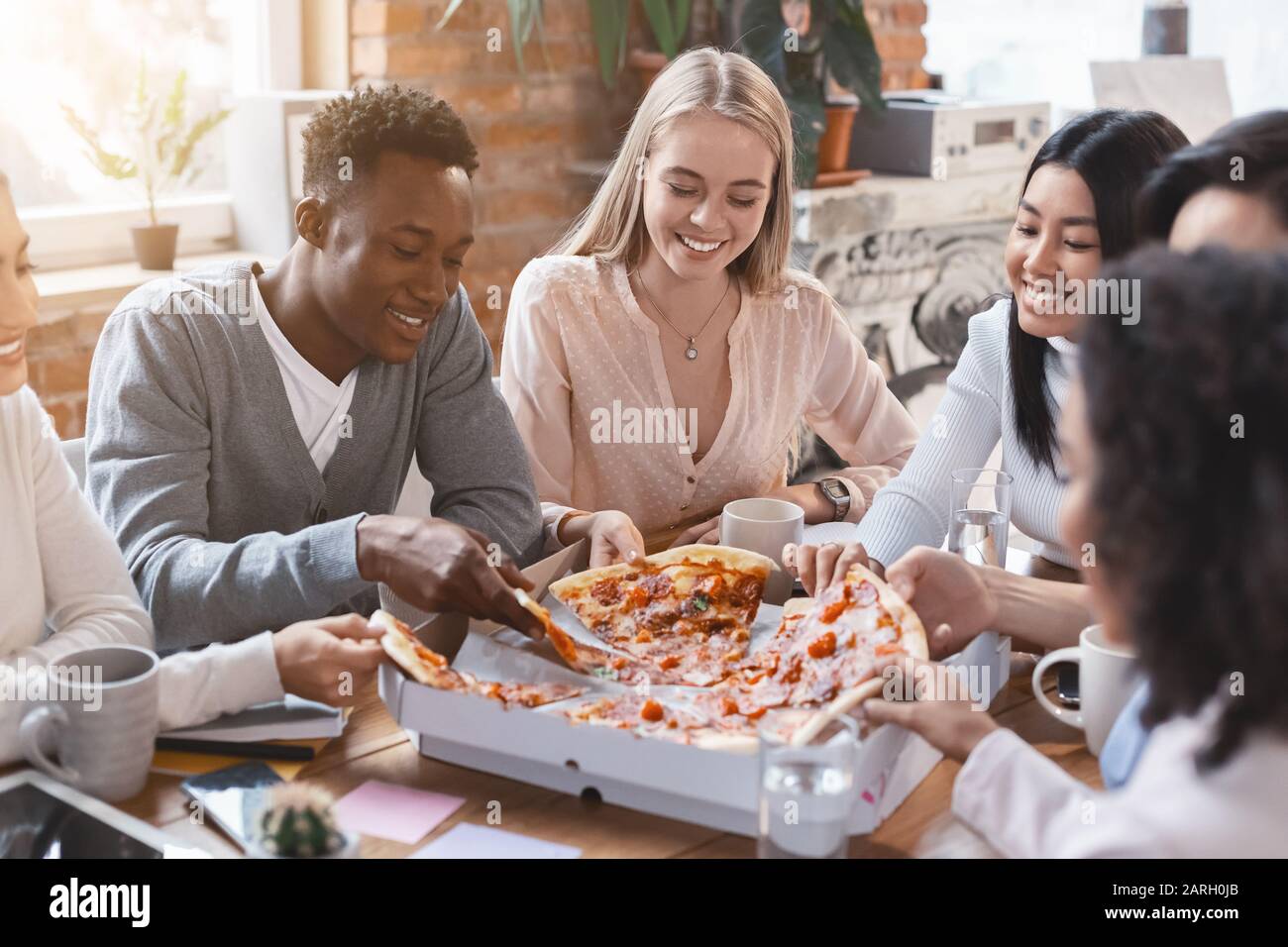 Happy multiracial colleagues eating pizza in office Stock Photo - Alamy