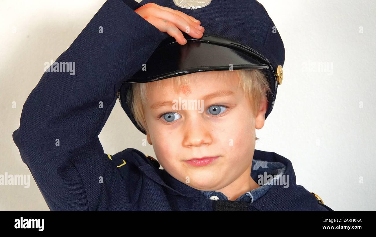 Six Year Old Boy Wearing Police Officer Fancy Dress  Outfit, Saluting Stock Photo