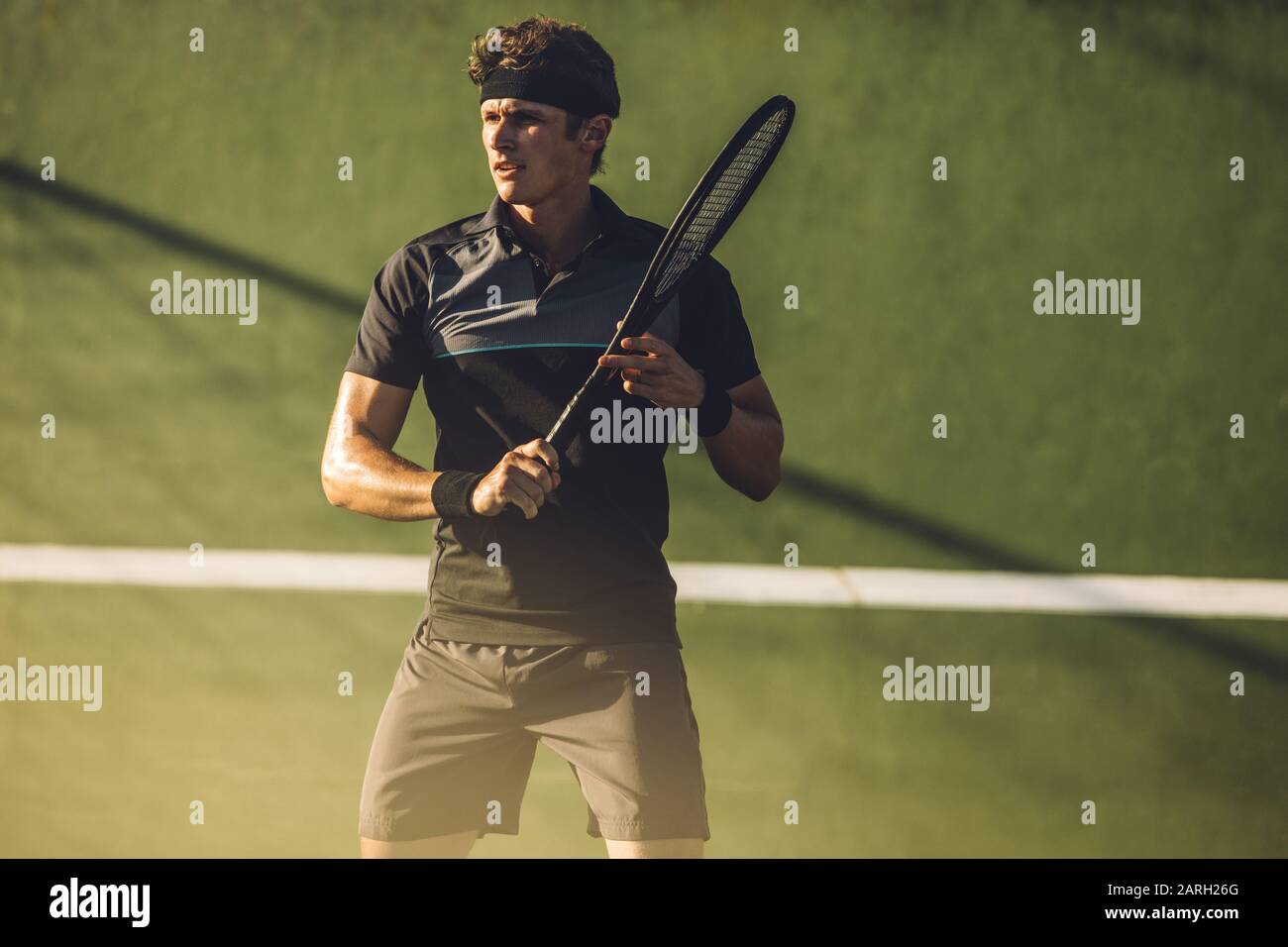 Professional tennis player with a racket on a tennis court. Tennis player playing on a hard court. Stock Photo