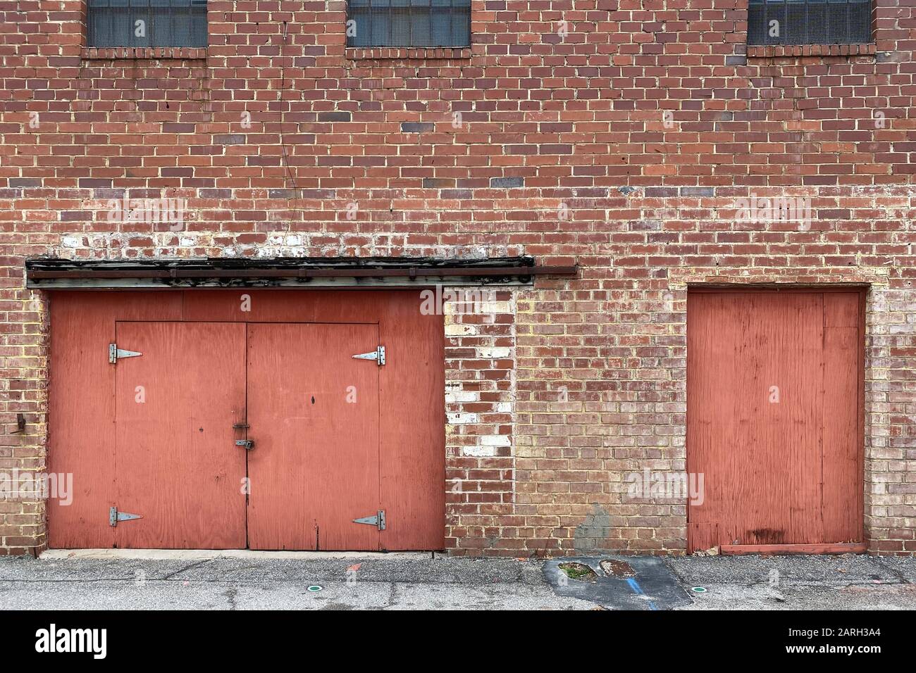 an abandoned warehouse alley brick wall with red doors Stock Photo Alamy
