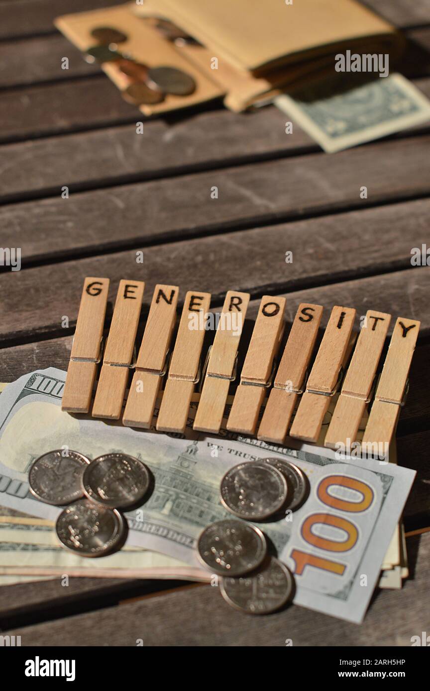 Plenty of money donated attached to wooden clothespins with the word GENEROSITY burnt into Stock Photo