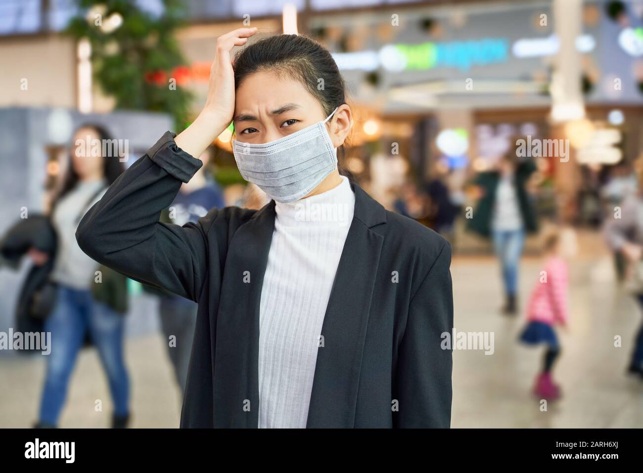 Alarmed female wears medical mask to protect Stock Photo