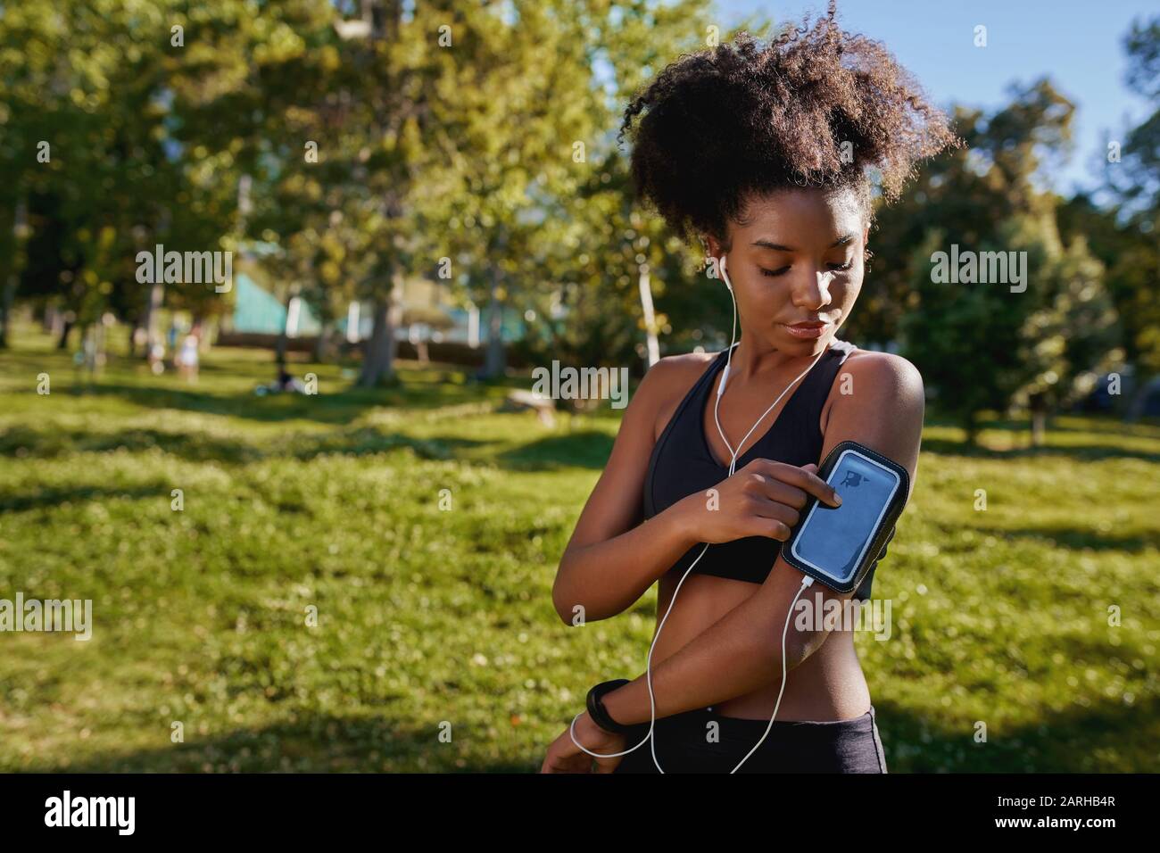Close-up of an african american female runner athlete listening to music from smart phone in armband - young active black woman  Stock Photo
