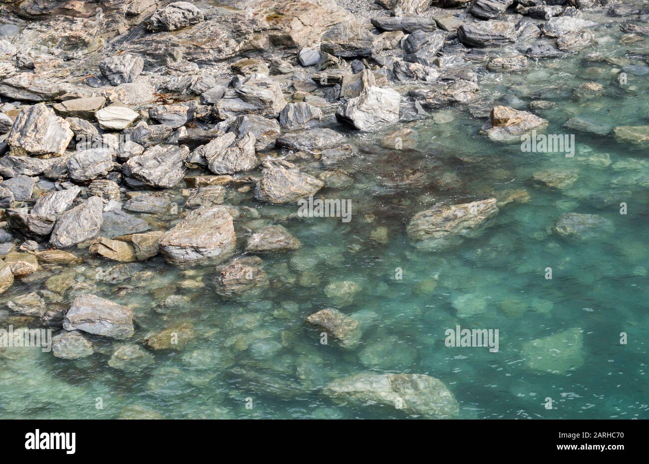 Crystal clear turquoise waters over rocks on the beach, Cornwall, UK Stock Photo