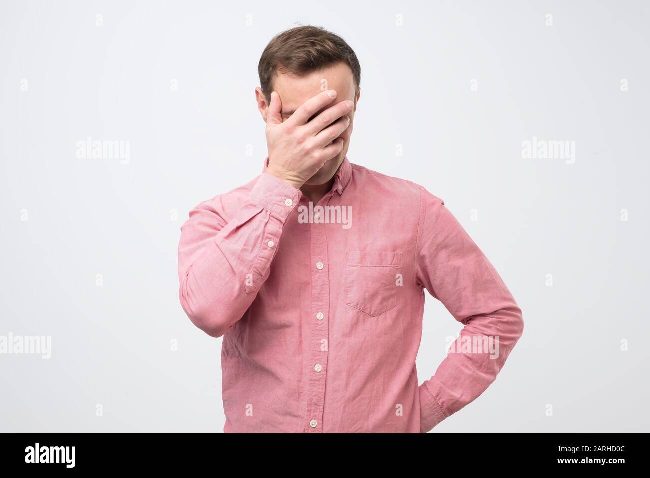 Shy embarrassed young man making faceplam gesture. Human reaction, feelings and attitude concept Stock Photo