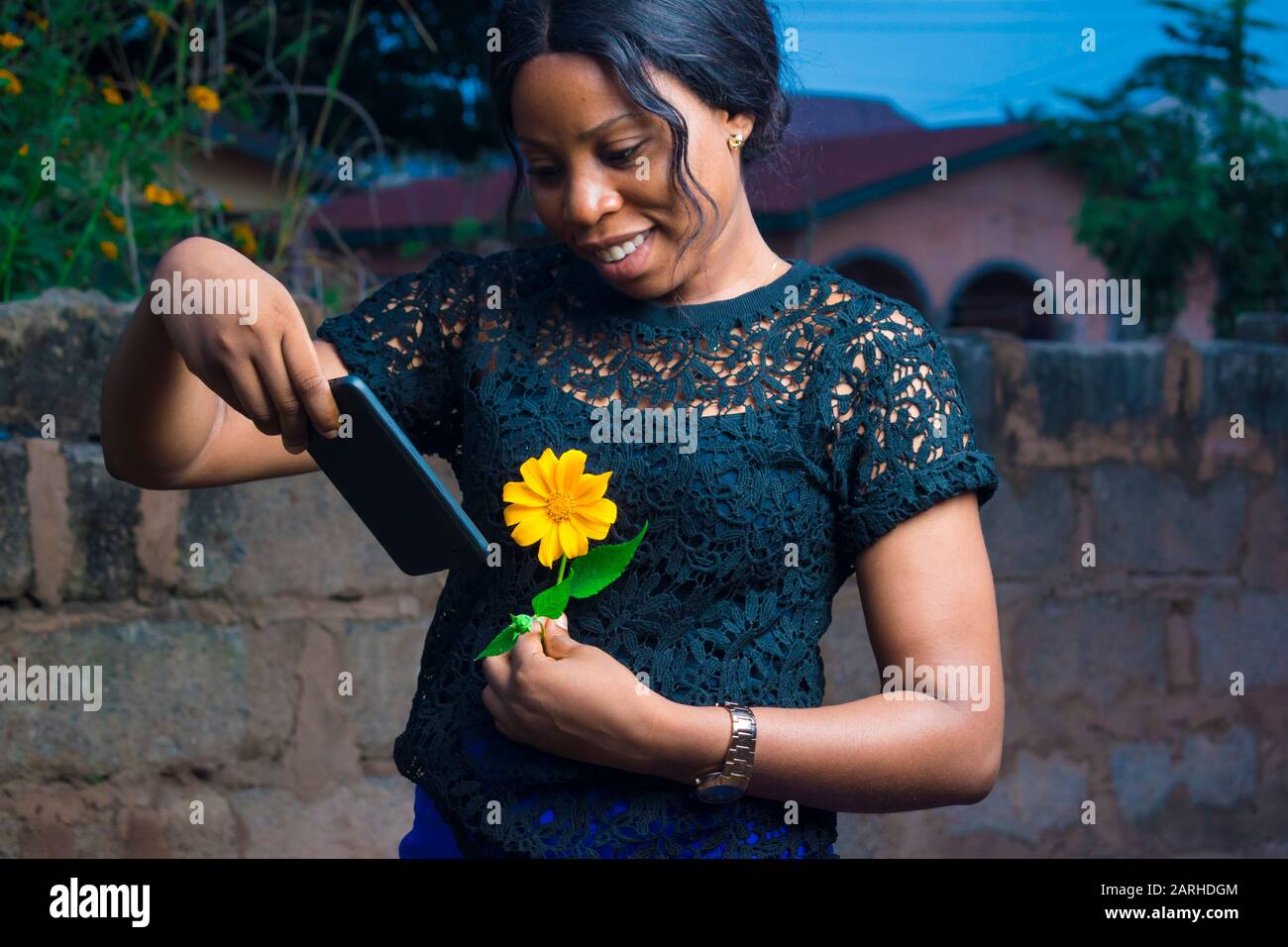 african girl holding a flower checks her mobile phone Stock Photo