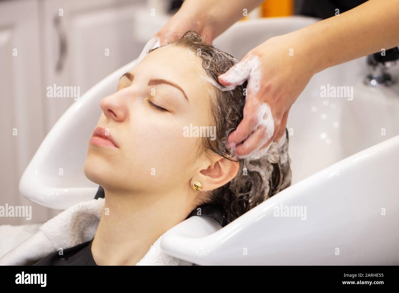 Hair washing at the hairdresser. Woman with closed eyes washes hair in the  bath Stock Photo - Alamy