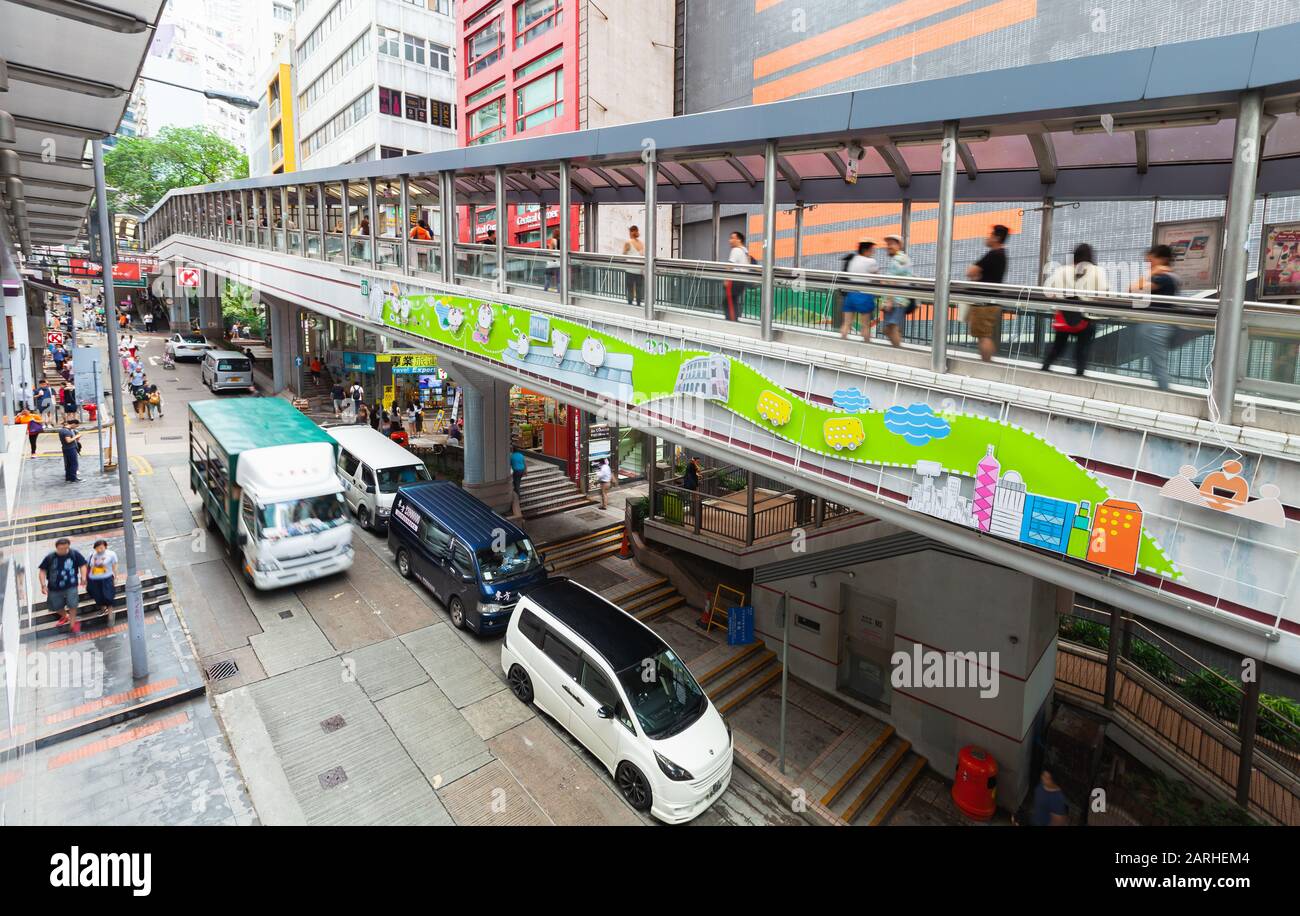 Hong Kong - July 15, 2017: Perspective street view with cars of Hong Kong central district. Ordinary people walk the street Stock Photo